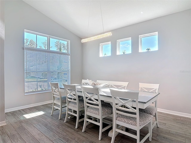 dining space featuring vaulted ceiling, wood finished floors, and baseboards