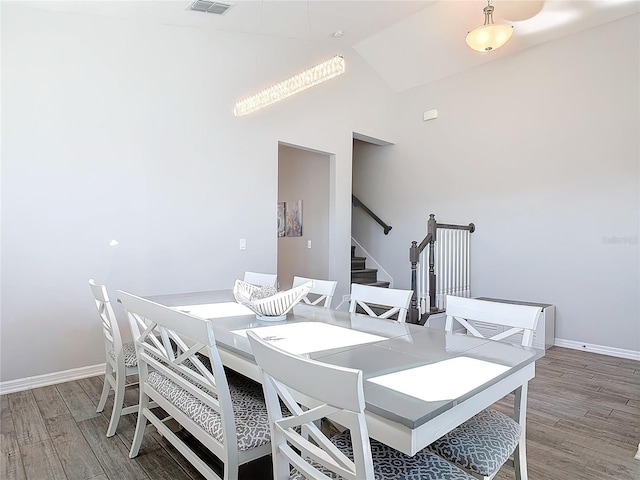 dining space with light wood-type flooring, visible vents, baseboards, and stairs