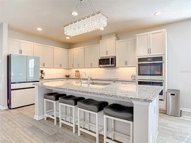 kitchen featuring appliances with stainless steel finishes, wood finish floors, a sink, and decorative backsplash