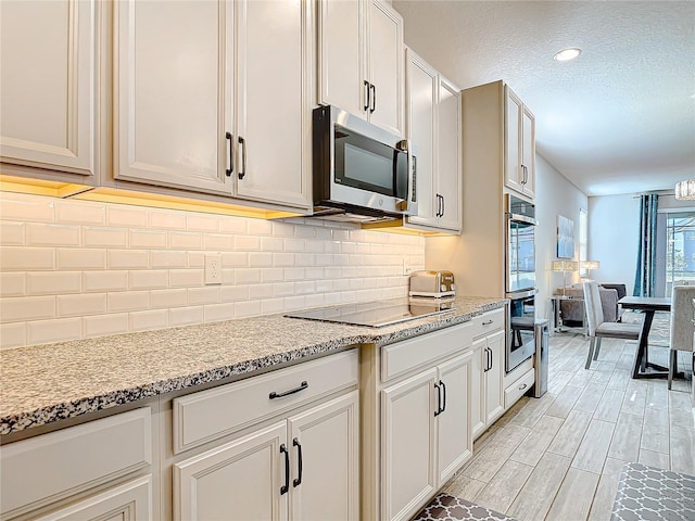 kitchen featuring tasteful backsplash, appliances with stainless steel finishes, light stone counters, wood tiled floor, and a textured ceiling