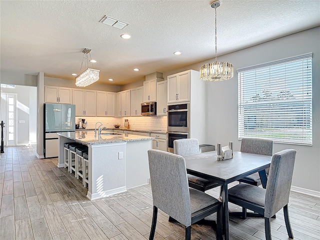 kitchen with stainless steel appliances, wood finish floors, visible vents, and a sink