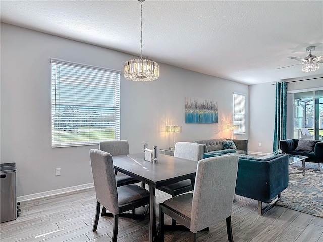 dining area with light wood finished floors, baseboards, and a textured ceiling