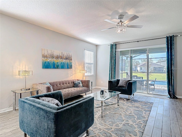 living room with wood tiled floor, ceiling fan, a textured ceiling, and baseboards