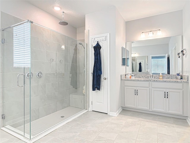 bathroom featuring a stall shower, vanity, and baseboards