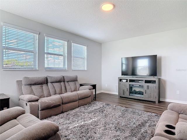 living area featuring a textured ceiling, dark wood-type flooring, and baseboards