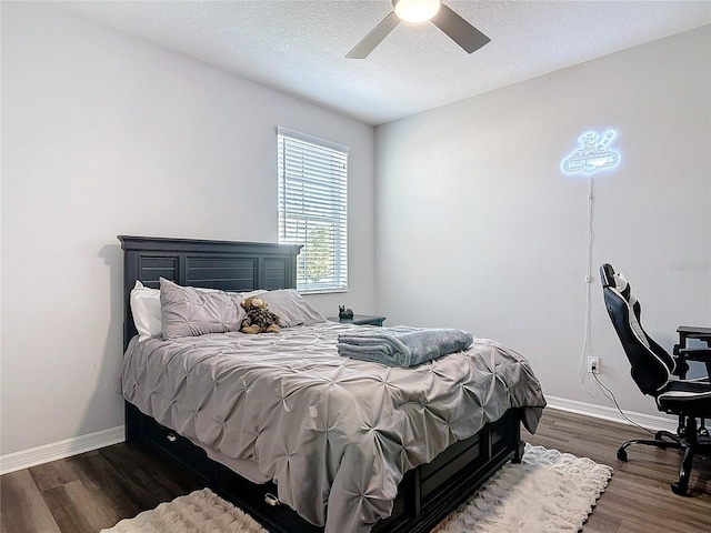 bedroom featuring ceiling fan, a textured ceiling, baseboards, and dark wood-style flooring