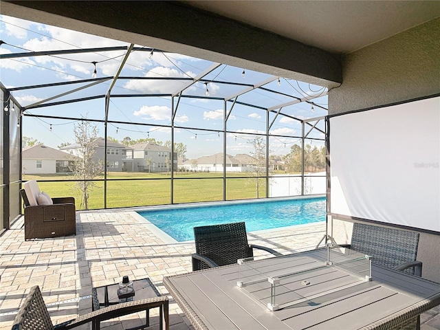 pool with a patio area, glass enclosure, and a yard