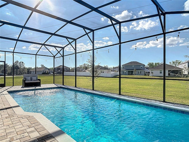 outdoor pool with a residential view, a patio area, glass enclosure, and a lawn