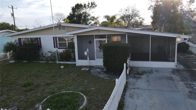 view of front facade featuring a sunroom, fence, and a front lawn