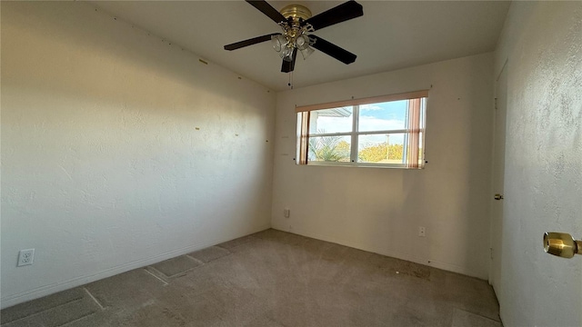 empty room featuring carpet floors, a textured wall, baseboards, and a ceiling fan