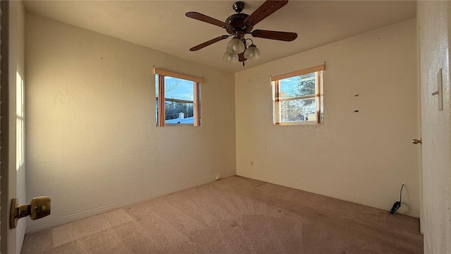 spare room with plenty of natural light, baseboards, a ceiling fan, and light colored carpet