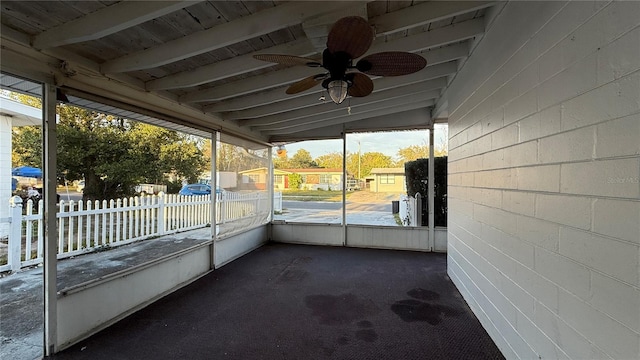 unfurnished sunroom with ceiling fan and beamed ceiling