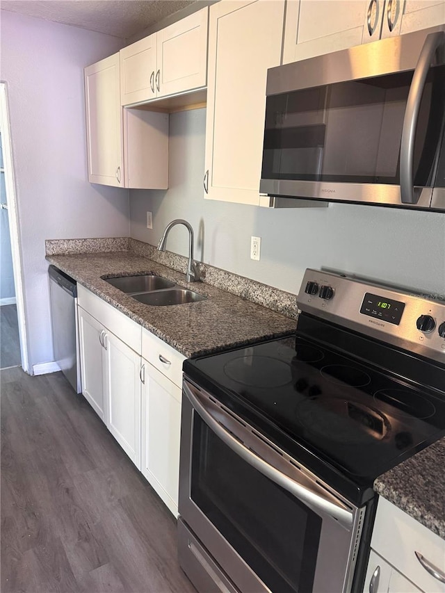 kitchen with stainless steel appliances, dark wood-type flooring, a sink, and white cabinetry