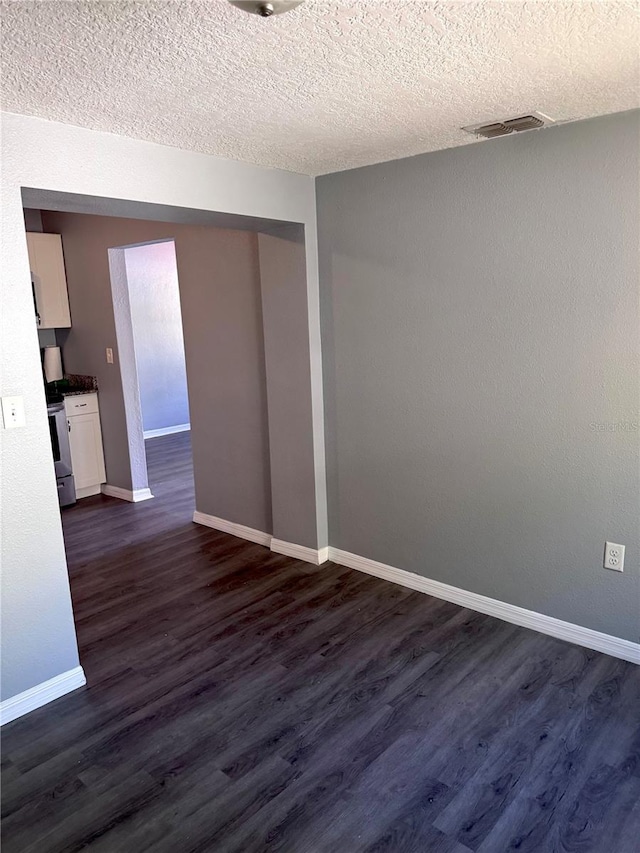 spare room featuring dark wood-style flooring, visible vents, a textured ceiling, and baseboards