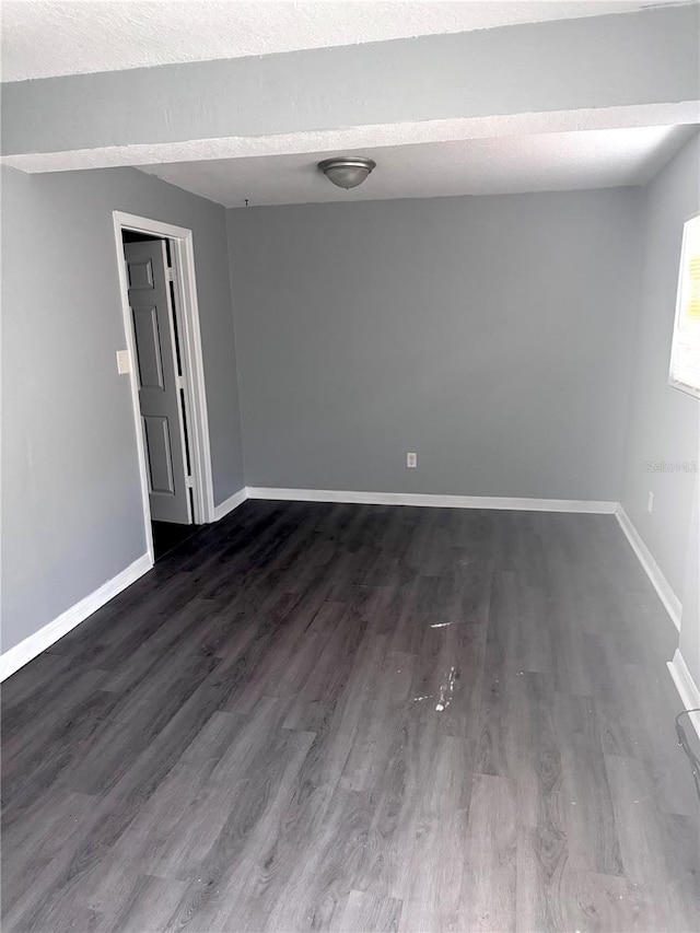 empty room with dark wood finished floors and baseboards