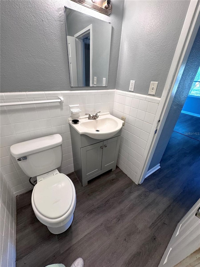 bathroom with toilet, vanity, wood finished floors, and wainscoting