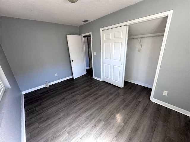 unfurnished bedroom featuring a closet, dark wood finished floors, visible vents, and baseboards