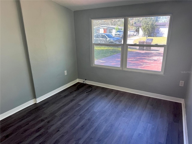 unfurnished room featuring dark wood-style floors and baseboards