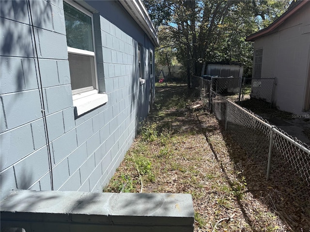 view of side of home featuring fence and concrete block siding