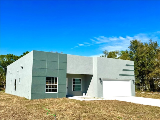 view of front of property featuring concrete driveway, an attached garage, and stucco siding