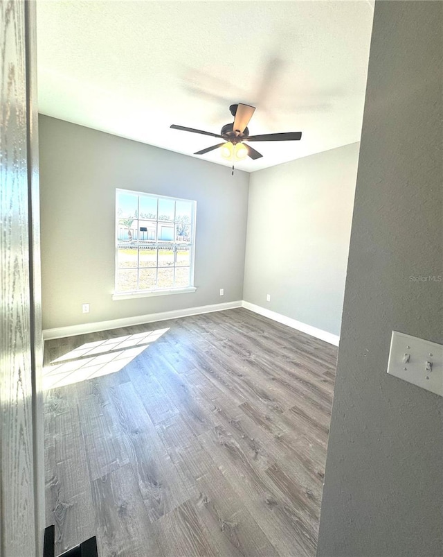 spare room featuring ceiling fan, baseboards, a textured ceiling, and wood finished floors