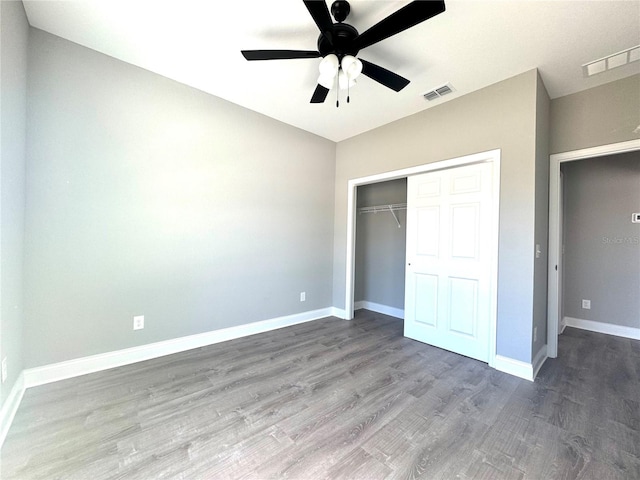 unfurnished bedroom featuring a closet, visible vents, baseboards, and wood finished floors