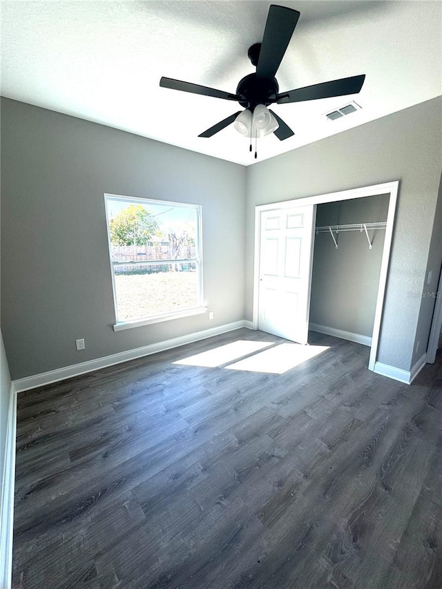 unfurnished bedroom featuring visible vents, baseboards, a closet, and dark wood-style flooring