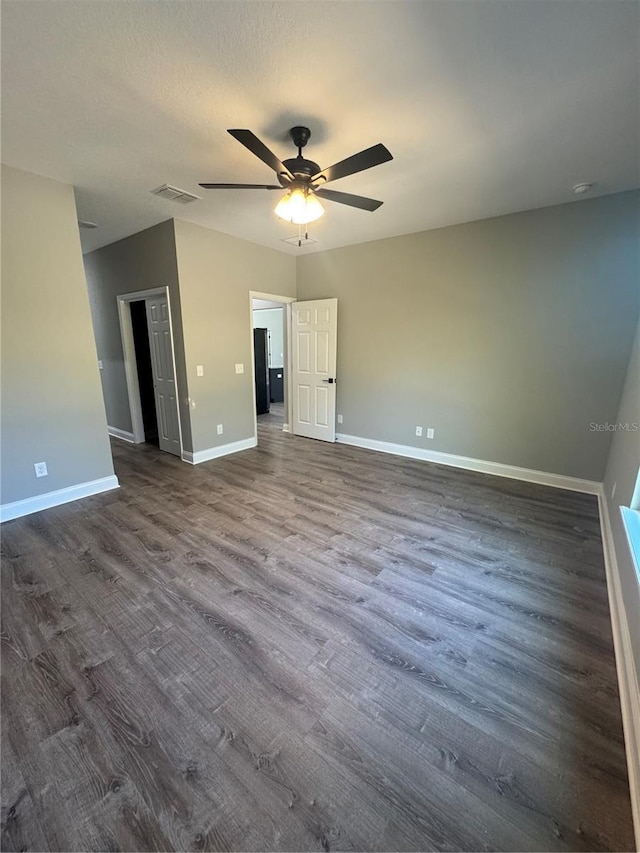 unfurnished room with dark wood finished floors, visible vents, ceiling fan, and baseboards