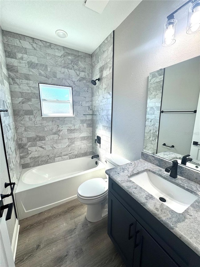 bathroom featuring vanity, wood finished floors, shower / washtub combination, toilet, and a textured wall