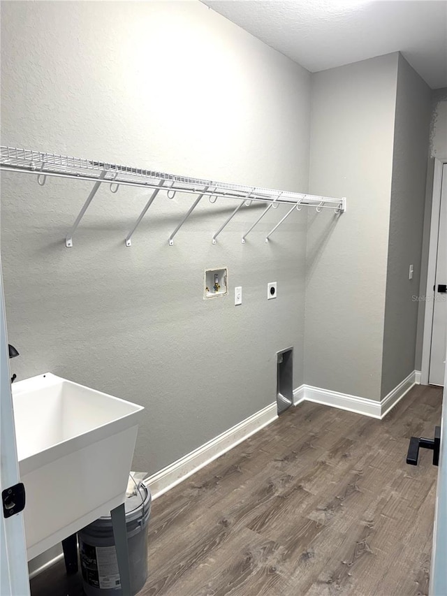 clothes washing area with a sink, wood finished floors, baseboards, hookup for a washing machine, and laundry area