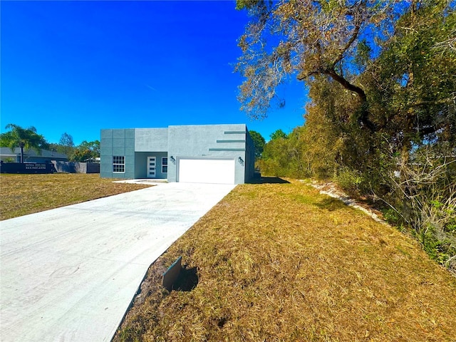 view of front of home featuring a garage, stucco siding, driveway, and a front lawn