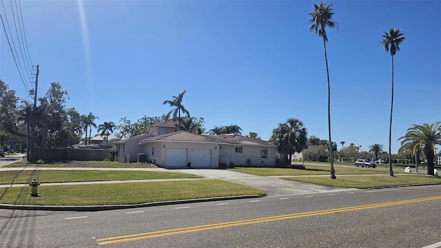 view of front facade with an attached garage, a front lawn, concrete driveway, and stucco siding