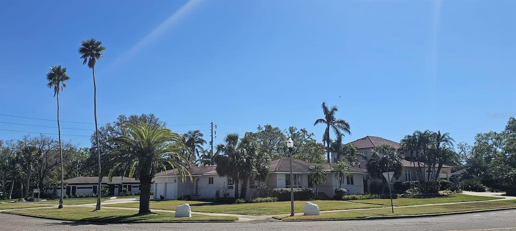 view of front of house featuring a garage, driveway, a front lawn, and a residential view