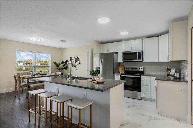 kitchen with tasteful backsplash, dark countertops, appliances with stainless steel finishes, marble finish floor, and a sink