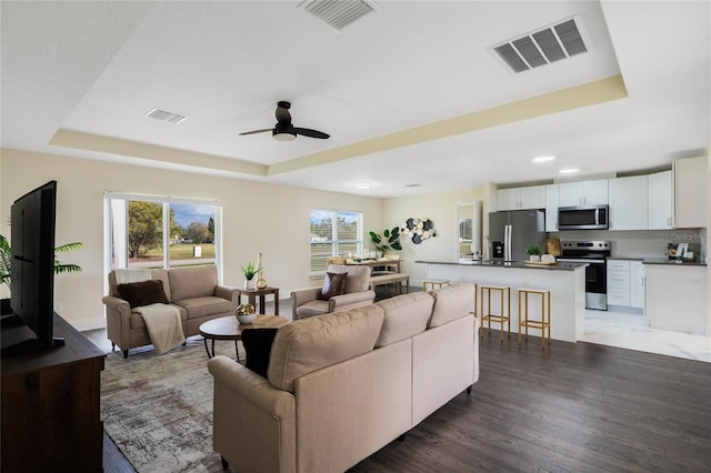 living area featuring a raised ceiling and visible vents