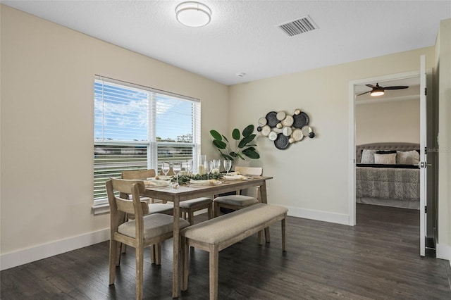 dining area featuring dark wood-style floors, baseboards, visible vents, and a textured ceiling