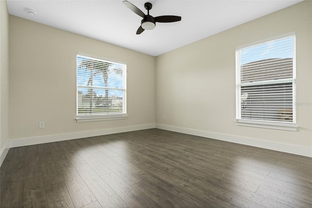 spare room with dark wood-style flooring, a ceiling fan, and baseboards