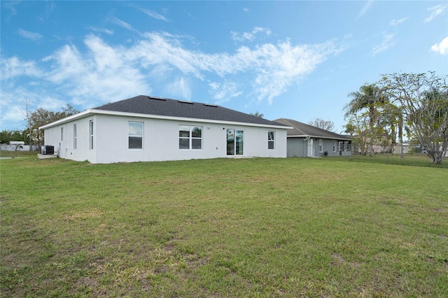 back of house with stucco siding and a yard