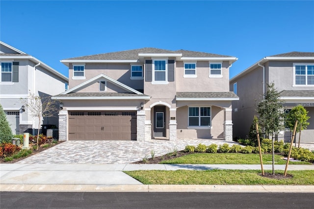 view of front of property with roof with shingles, central AC unit, decorative driveway, and stucco siding