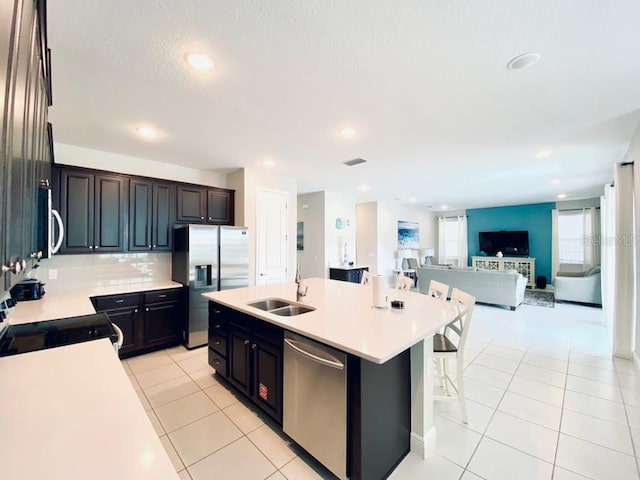 kitchen featuring light tile patterned floors, tasteful backsplash, appliances with stainless steel finishes, open floor plan, and a sink