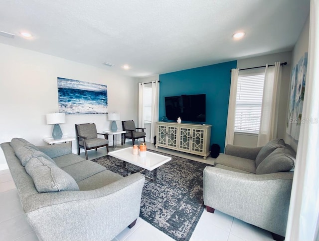 living area featuring tile patterned flooring, visible vents, a textured ceiling, and recessed lighting