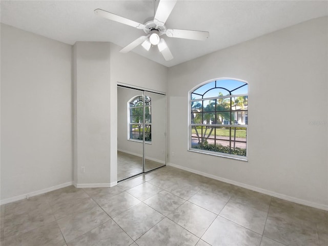 unfurnished bedroom with light tile patterned floors, a closet, a ceiling fan, and baseboards