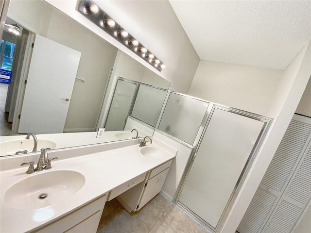 full bathroom with a textured ceiling, double vanity, tile patterned flooring, and a sink