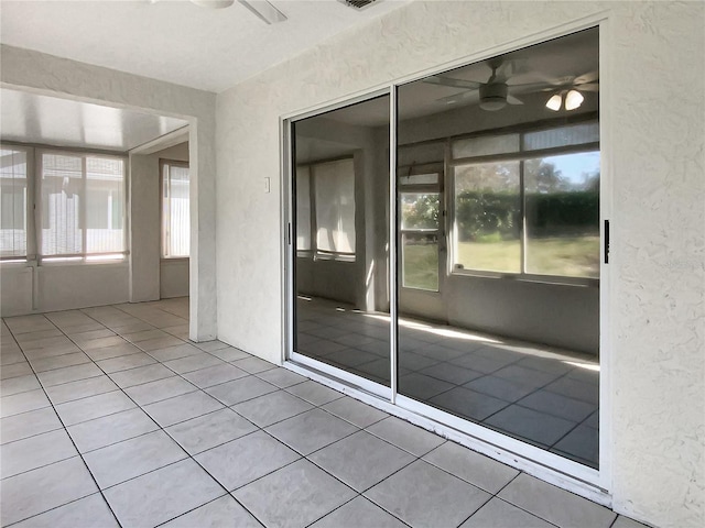 unfurnished sunroom featuring a wealth of natural light, visible vents, and ceiling fan
