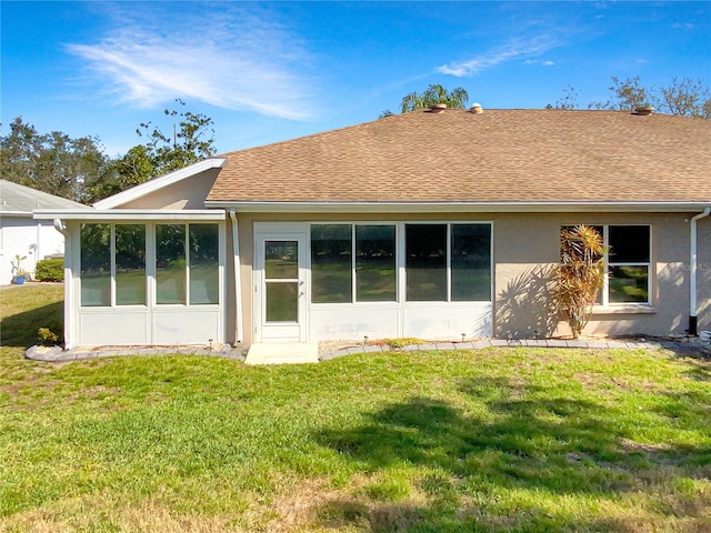 back of house featuring a yard, roof with shingles, a sunroom, and stucco siding