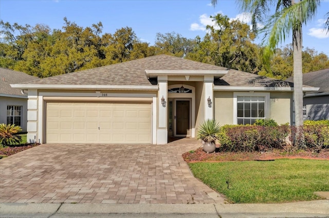 view of front of property featuring stucco siding, a shingled roof, decorative driveway, and a garage