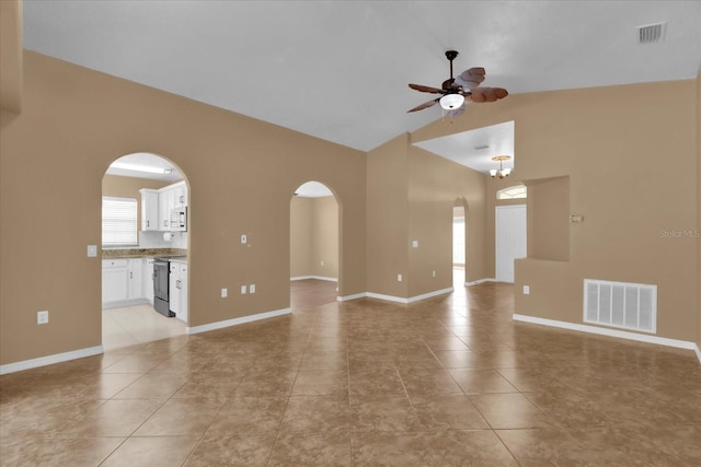 empty room with visible vents, arched walkways, light tile patterned flooring, and a ceiling fan