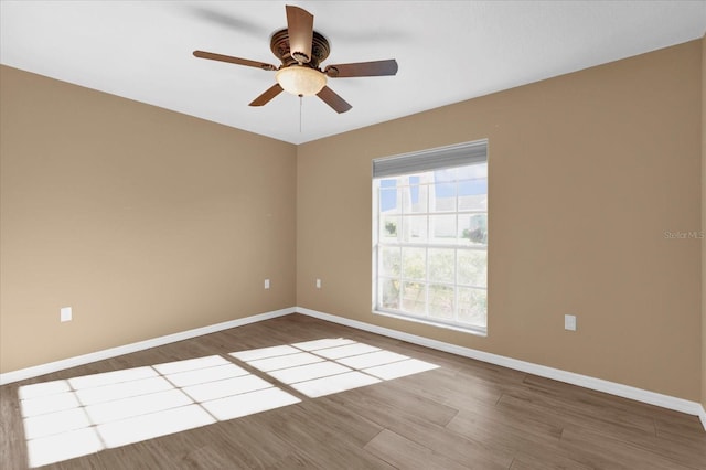 empty room with a ceiling fan, wood finished floors, and baseboards