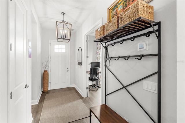 entrance foyer featuring baseboards, a chandelier, and wood finished floors