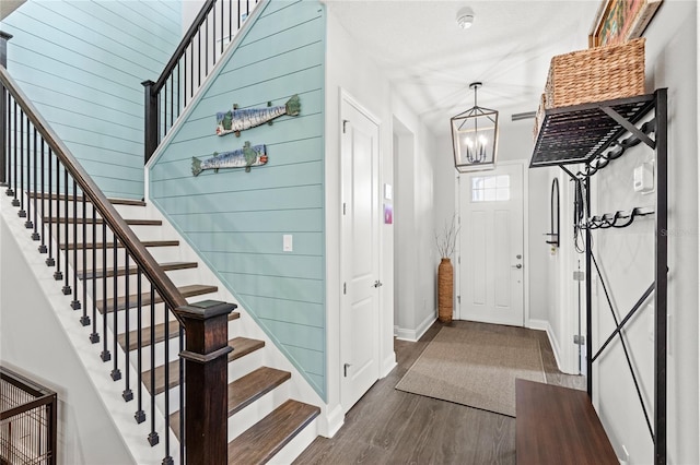 interior space with baseboards, a notable chandelier, stairway, and wood finished floors